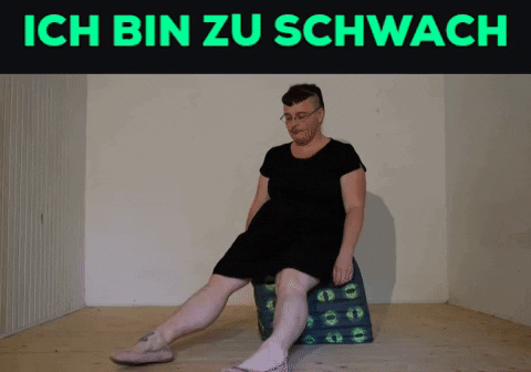 Ein Gif. Oben in Knallgrün auf Schwarzem Grund die Worte: ich bin zu schwach. Darunter versucht Tristan Marie sich auf einen würfelförmigen Polsterhocker zu setzen. Nin findet kein Gleichgewicht und rutscht ganz langsam vorwärts vom Hocker.
