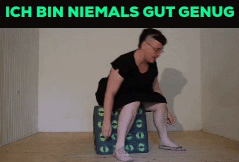 Ein Gif. Oben in Knallgrün auf Schwarzem Grund die Worte: ich bin niemals gut genug. Darunter versucht Tristan Marie sich auf einen würfelförmigen Polsterhocker zu setzen. Nin findet kein Gleichgewicht und fällt mit dem Hocker hintenüber. Im Fall wedelt nin mit dem Armen.