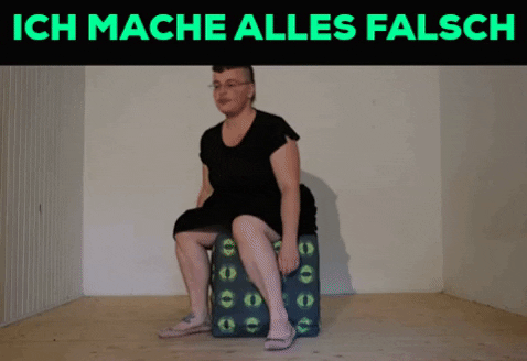 Ein Gif. Oben in Knallgrün auf Schwarzem Grund die Worte: ich mache alles falsch. Darunter versucht Tristan Marie sich auf einen würfelförmigen Polsterhocker zu setzen. Nin findet kein Gleichgewicht und kippt mit dem Hocker nach rechts um.