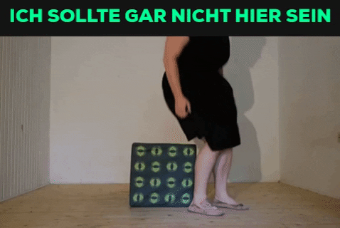 Ein Gif. Oben in Knallgrün auf Schwarzem Grund die Worte: ich sollte gar nicht hier sein. Darunter versucht Tristan Marie sich auf einen würfelförmigen Polsterhocker zu setzen. Nin findet kein Gleichgewicht und rutscht vorwärts vom Hocker. Auf dem Boden sitzend versucht Tristan marie sich gegen den Hocker zu lehnen. der rutscht nach hinten weg. Schließlich liegt Tristan Marie auf dem Boden.