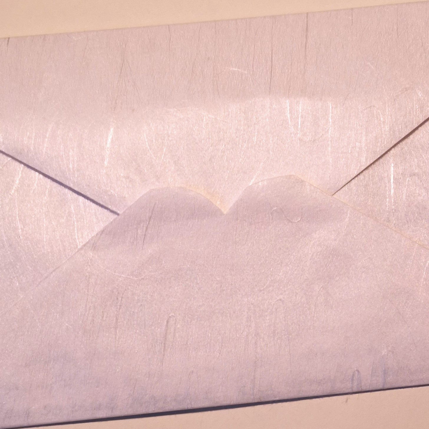 Bildausschnitt von einem Brief. Der Umschlag ist aus feinem Papier gefertigt und überzogen mit einem glänzenden, hauchdünnen Papier aus Kunstseidefasern.